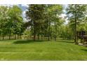 Expansive backyard featuring lush lawn, mature trees, and tranquil pond views from the property line at 1527 Canyon Oak Ln, Columbus, IN 47201