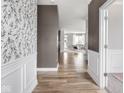 Inviting hallway with decorative wallpaper, wainscoting, and wood-look floors leading to the living area at 5832 Lyster Ln, Indianapolis, IN 46239