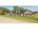 Angle view of a brick home with lush lawn, a three car garage and mature trees at 6017 Quail Creek Blvd, Indianapolis, IN 46237
