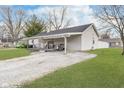 Single-story home with vinyl siding, covered porch, long gravel driveway and a well kept lawn at 654 Park Dr, Greenwood, IN 46143