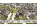 An aerial shot features a lovely home with an extended driveway, manicured yard, and mature trees at 9931 Woodlands Dr, Fishers, IN 46037