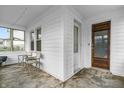 The sunroom features neutral colors, three chairs, and a wooden front door to welcome guests at 1655 Cornell Ave, Indianapolis, IN 46202