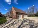 Two-car garage with gray doors, basketball court and mature trees on a sunny day at 3610 Eagle Emblem Ct, Greenwood, IN 46143
