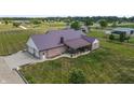 An aerial view captures a brick home with metal roof, a patio, an attached garage, and verdant surroundings at 3777 S 300 E, Anderson, IN 46017