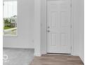 Bright entryway features white front door, light gray carpet, wood flooring and a view of the outside through a window at 4739 E Shadowbrook Dr, Camby, IN 46113