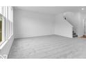 Large living room with neutral carpet, white walls and trim, a window and staircase leading to the upper level at 4739 E Shadowbrook Dr, Camby, IN 46113