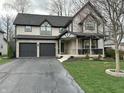 Beautiful home featuring an attached two-car garage, a charming porch, and a well-kept lawn at 5018 Melbourne Rd, Indianapolis, IN 46228