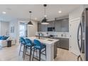 A modern kitchen with gray cabinets, an island with blue chairs, and stainless steel appliances at 5771 Cr W 750 N, McCordsville, IN 46055