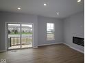 Bright living room with wood flooring, sliding door to balcony, and a modern fireplace at 7089 Pate Hollow Dr, Brownsburg, IN 46112