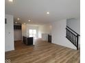 Open-concept living space with wood floors flows into a modern kitchen and staircase at 7093 Pate Hollow Dr, Brownsburg, IN 46112