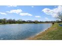 Peaceful lakeside view with clear blue water reflecting the sky, framed by grassy shores and distant trees at 7253 Sunset Point Dr, Indianapolis, IN 46259