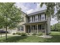 Charming two-story home with brick accents, black shutters, a front porch, and landscaped front yard at 7448 Giroud Dr, Indianapolis, IN 46259