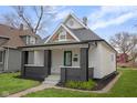Charming home featuring a peaked gable roof, gray brick accents, and a well maintained yard at 843 N Oxford St, Indianapolis, IN 46201