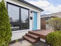 Inviting front porch with a bright blue door, wooden steps, and well-maintained landscaping at 928 E Pleasant Run Parkway North Dr, Indianapolis, IN 46203