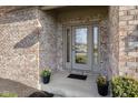 Inviting front entryway with decorative glass door, planters, and brick facade at 1114 Woodridge, Brownsburg, IN 46112