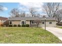 Well-maintained single-story home with stone and light green siding, featuring a neat lawn and mature shrubbery at 1400 W Cowing Dr, Muncie, IN 47304