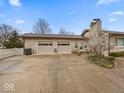 Spacious two-car garage and stone chimney, complemented by a well-kept driveway and landscaped front yard at 1418 E Maple Dr, Shelbyville, IN 46176