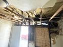 Interior view showing exposed ceiling joists, damaged walls and floors at 1437 Kappes St, Indianapolis, IN 46221