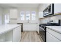 Close-up of white kitchen with stainless appliances, quartz countertops, modern faucet, and luxury vinyl plank flooring at 14556 Hanford Ln, Carmel, IN 46074