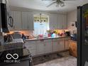 Functional kitchen with white cabinets, modern stainless steel appliances, and laminate flooring at 1635 N Lynhurst Dr, Indianapolis, IN 46224