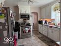Functional kitchen with white cabinets, modern stainless steel appliances, and laminate flooring at 1635 N Lynhurst Dr, Indianapolis, IN 46224