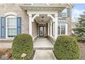 Inviting front porch with white pillars, a glass front door, trimmed shrubs, and meticulous landscaping at 209 North Bnd, Greenwood, IN 46142