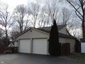 Two-car garage with paneled doors adjacent to a lush, landscaped yard at 269 Iron Bridge Rd, Cicero, IN 46034