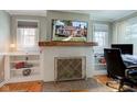 Bright living room featuring a brick fireplace with a wooden mantle, built-in shelving, and a large screen tv at 5937 Guilford Ave, Indianapolis, IN 46220