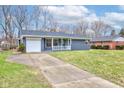 View of the lovely brick home with an attached garage, and concrete driveway and beautiful lawn at 6503 W 15Th St, Indianapolis, IN 46214
