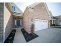 Inviting front entrance with a gray door, complemented by beautiful landscaping and an attached two car garage at 7713 Imperial Eagle Dr, Zionsville, IN 46077