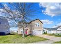 Charming two-story home with a well-maintained lawn, a garage and a pink front door with wreath at 8110 Crackling Ln, Indianapolis, IN 46259