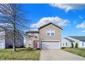 Charming two-story home with a well-maintained lawn, a garage and a pink front door with wreath at 8110 Crackling Ln, Indianapolis, IN 46259