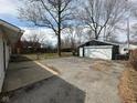 Backyard view showcasing a detached garage and a gravel parking area for additional vehicles or storage at 4224 N Arlington Ave, Indianapolis, IN 46226