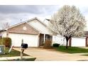 Exterior view of house featuring garage, brick accents, and flowering tree in the front yard at 5437 Powder River Ct, Indianapolis, IN 46221