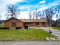 Charming brick home featuring a ramp, attached garage, and well-manicured lawn at 619 Heritage Ln, Anderson, IN 46013
