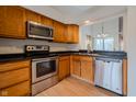 Functional kitchen with stainless steel appliances, wood cabinets, and a pass-through to the dining area at 7352 Crickwood Pl, Indianapolis, IN 46268