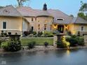 Beautiful home featuring manicured lawn and garden beds, framed by stone entrance and stone turret at 10821 Club Point Dr, Fishers, IN 46037