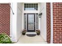 Close up of entryway with a black front door, potted plants, and brick accents at 1361 Colinbrook Ct, Greenwood, IN 46143