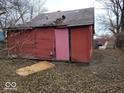 Rear exterior of a red house needing repair, with damage to the roof and siding at 1724 Sheldon St, Indianapolis, IN 46218