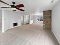 Spacious living room with a ceiling fan, fireplace, and a wall with rustic wood paneling at 3313 Capsella Ln, Indianapolis, IN 46203