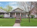 Inviting home with a covered porch, vibrant lawn, and tidy landscaping, creating a delightful first impression at 518 N Emerson Ave, Indianapolis, IN 46219