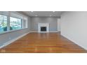 Sun-filled living room featuring hardwood floors, fresh paint, fireplace and large window at 6407 Brokenhurst Rd, Indianapolis, IN 46220