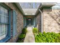 Inviting entryway with brick facade, front door, and lush landscaping along the walkway at 7616 Newport Bay E Dr, Indianapolis, IN 46240