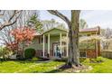 Charming green home featuring a bright blue front door surrounded by mature trees at 7859 N Chester Ave, Indianapolis, IN 46240