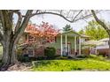 Inviting green home with colorful landscaping, including blooming trees and shrubs at 7859 N Chester Ave, Indianapolis, IN 46240