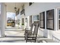 Inviting front porch featuring white columns, rocking chairs, and stylish exterior lighting fixtures at 8020 N Meridian N St, Indianapolis, IN 46260