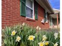 Close up of brick siding and green shutters with spring flowers in bloom at 810 Fabyan Rd, Indianapolis, IN 46217