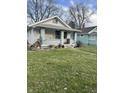 This single-story home has a covered porch with decorative planters and a satellite dish at 1409 N Denny St, Indianapolis, IN 46201