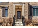 Close-up view of a stylish front door with glass inserts, framed by elegant brickwork and a well-lit porch at 15628 Allegro Dr, Westfield, IN 46074