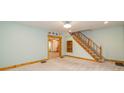 Carpeted living room with wood trim, staircase, and view to the kitchen at 241 S Walnut St, Jamestown, IN 46147
